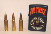 Photo of three 5.7x28mm cartridges as used in the P90. The left cartridge has a plain hollow tip, the center cartridge has a red plastic V-max tip, and the right cartridge has a blue plastic V-max tip.